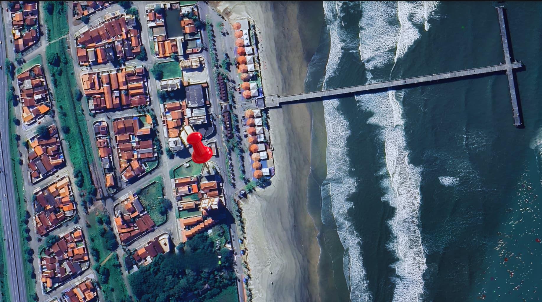 Vista aérea mostrando a pousada na beira da praia, ao lado da plataforma de pesca
